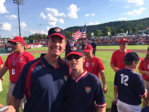 Father and son, Dan and Luke Adams, pose on the field in their Cooperstown gear.